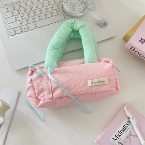 Close-up of pink quilted Sorakka pencil case with green handle and blue ribbon detail
