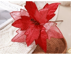 Detailed close-up of a red poinsettia flower with gold glitter on a cozy knit blanket