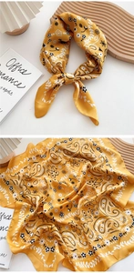 Detail of yellow paisley silk scarf with vintage floral patterns and knotted styling
