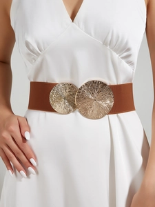 Detail of a brown elastic waist belt featuring large gold circular metallic textured buckles