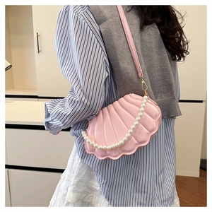 Detail showing the pink shell-shaped bag with pearl handle and striped texture