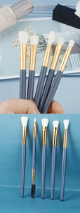 Detail of blue eye makeup brushes with cream bristles and elegant gold ferrules set