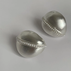Dettaglio di orecchini vintage in argento opaco con accenti di intarsio in perle