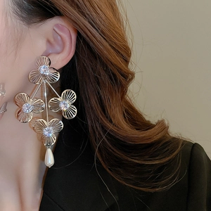Close-up of oversized silver flower earrings with zircon and pearls on a model wearing black