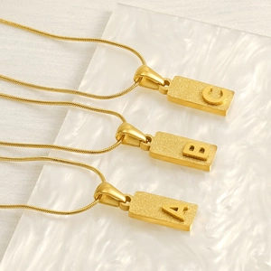 Gold stainless steel rectangle pendant necklaces with frosted letters A B C on marble