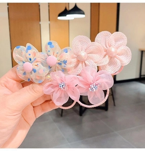 Primer plano de tres gomas de pelo de flores de gasa rosa con lunares para niñas