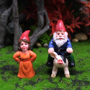 Funny garden gnome figurines featuring a female gnome and a male gnome riding a pig