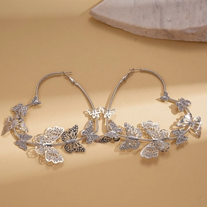 Dettaglio di orecchini a cerchio argento con farfalle di strass e design in metallo