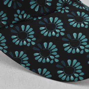 Close-up of black ponytail baseball cap brim featuring cyan floral print and twill texture