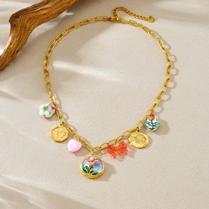 Detail of vintage gold necklace featuring enamel flower and butterfly relief charms