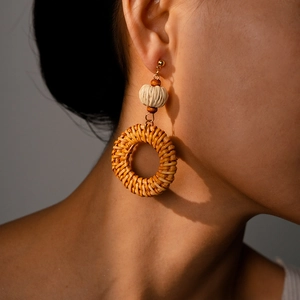 Macro detail of natural resin rattan woven hoop earrings on model for resort style