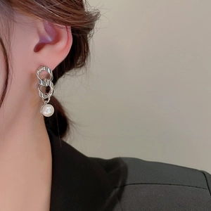 Detail of silver chain earrings with white pearl pendant on model wearing black blazer