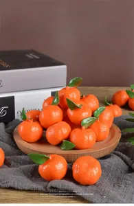 Detailed close-up of realistic PVC mini oranges with green leaves on a wooden tray