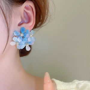 Detailed view of 3D blue gradient acrylic flower earrings on model's ear