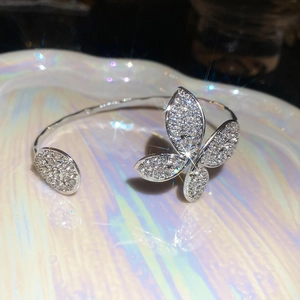 Detailed view of silver butterfly open bracelet with pavé diamonds on pearlescent surface