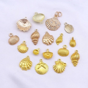 Flat lay of gold and rose gold sea shell and starfish charms with rhinestones on white