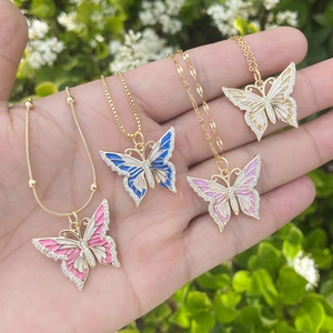 Golden butterfly pendant necklaces set with pink, blue and white crystals on hand