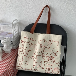 Detail of artistic canvas tote bag featuring cute hand-drawn cat illustrations on a chair