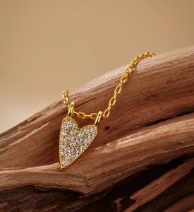Close-up of gold plated heart pendant necklace with pavé zircons on natural wood