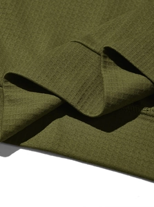 Detailed close-up of olive green waffle knit fabric and ribbed cuff craftsmanship on polo shirt