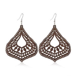 Macro detail of dark brown wooden earrings with geometric hollow-out teardrop pattern