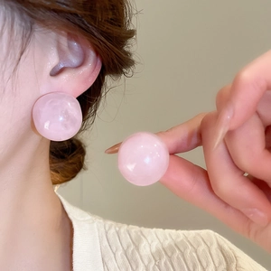 Close-up of pink round resin stud earrings worn on ear showing elegant size and luster