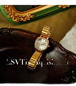 Detail view of a vintage gold women's quartz watch placed on an ornate wooden tray