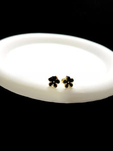 Macro detail of minimalist black enamel flower stud earrings with elegant gold borders