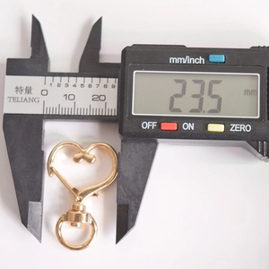 Detail showing width measurement of a heart-shaped gold alloy swivel lobster clasp