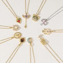 Flat lay of gold tone heart and magic wand pendant necklaces on white fabric background