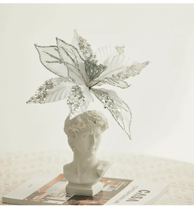 Artistic close-up of white sheer poinsettia with silver glitter on white David statue