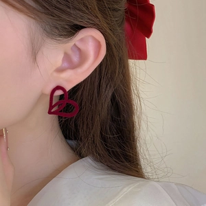 Elegant red flocked heart earrings with bow detail shown on professional model