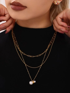 Close-up of golden triple-layered necklace with pearl and crystal pendants and earrings