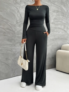Detail of black long sleeve top with asymmetrical neckline and ruched waist accents