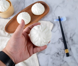 Detailed view of an 8cm white squishy bun toy on a mini steamer with wooden chopsticks