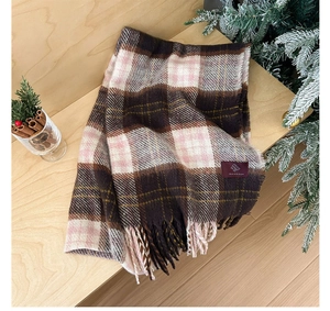 Macro detail of plaid tassel scarf with soft wool texture and elegant brand label