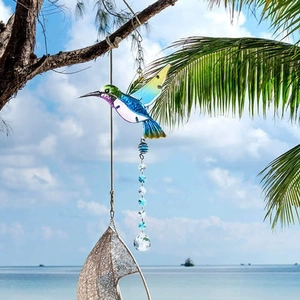 Vibrant hummingbird suncatcher with crystal ball hanging on a palm tree by the sea