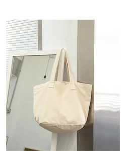 Detailed view of a vintage beige canvas tote bag hanging in a minimalist interior setting