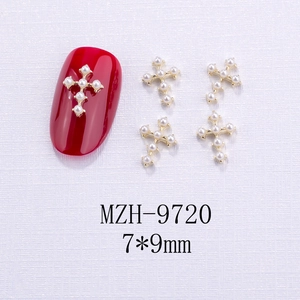 Ciondoli per unghie a croce dorata con perle 7x9mm su una manicure di colore rosso