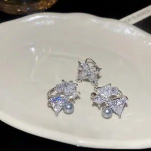 Sparkling zircon bow and star ear clips set on cream ceramic tray with high contrast