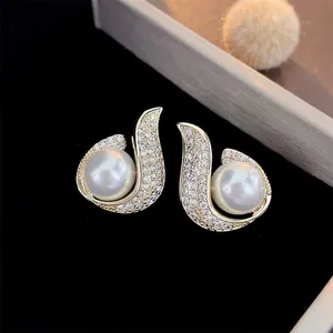 Luxurious gold-plated leaf earrings with pearls and pavé zircons on black velvet