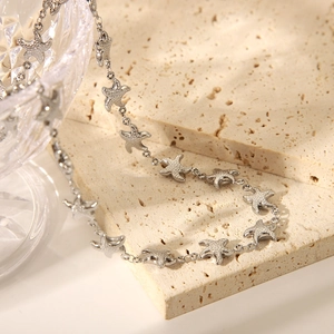 Detail of silver starfish charm bracelet draped over a textured stone and crystal glass