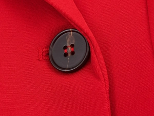 Close-up of red twill fabric texture and dark brown tortoiseshell button on blazer