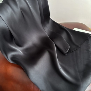 Close-up of black satin silk scarf with elegant sheen and smooth texture on leather
