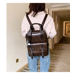 Detail view of deep brown vintage PU leather backpack with buckle on model