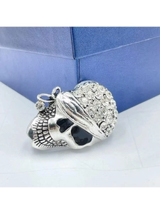 Close-up of a silver skull brooch with white rhinestones leaning on a blue jewelry box
