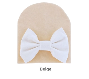 Detail of baby beanie with a large white decorative bow on soft cream knitted fabric