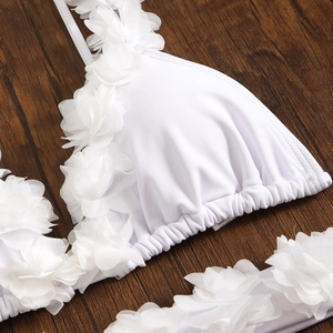 Detailed view of white bikini top featuring 3D mesh flower petals on wood background
