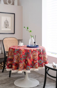 Detail of red round tablecloth with colorful geometric patterns and white tassels