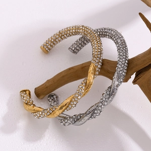 Details des gedrehten Kabelarmreifs in Gold und Silber mit eingelegten Zirkonia-Steinen